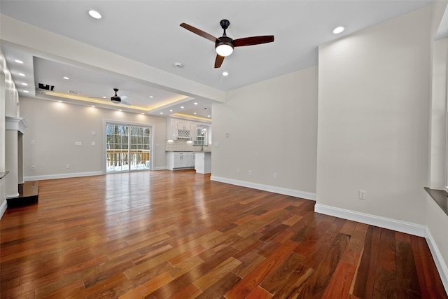 unfurnished living room with ceiling fan, wood-type flooring, and a raised ceiling