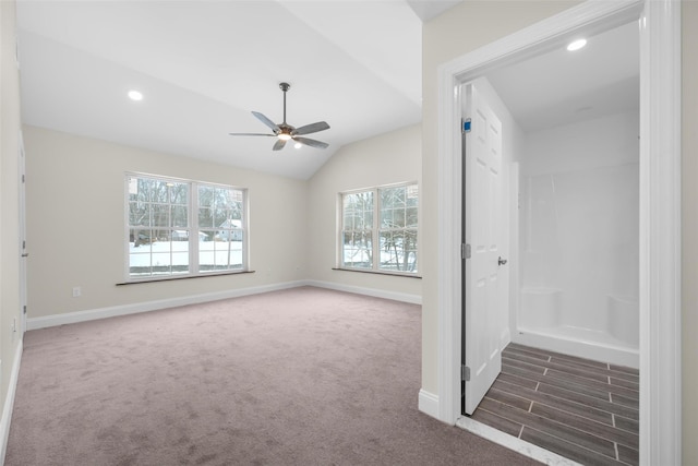 interior space with dark colored carpet, vaulted ceiling, and ceiling fan