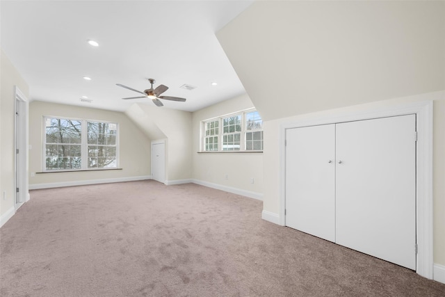 additional living space with ceiling fan, light colored carpet, and a healthy amount of sunlight