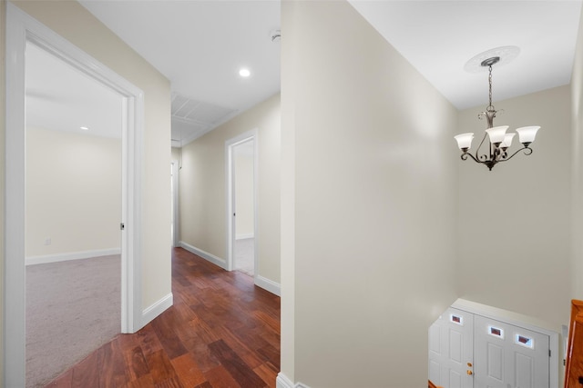 hallway featuring dark wood-type flooring and a chandelier