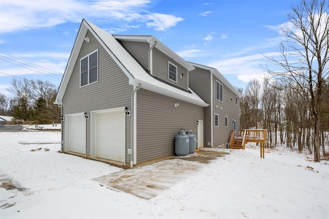 snow covered property featuring a garage and a deck