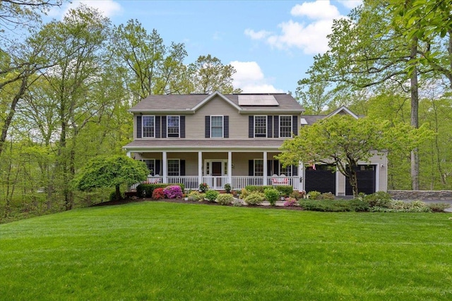6 W Causeway, Cortlandt Manor, NY 10567 - colonial home featuring covered porch, a garage, roof mounted solar panels, and a front lawn