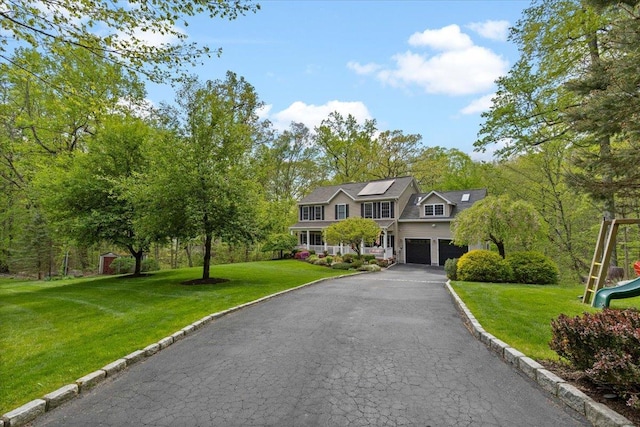 6 W Causeway, Cortlandt Manor, NY 10567 - view of front of home with a garage, a front yard, a playground, driveway, and solar panels