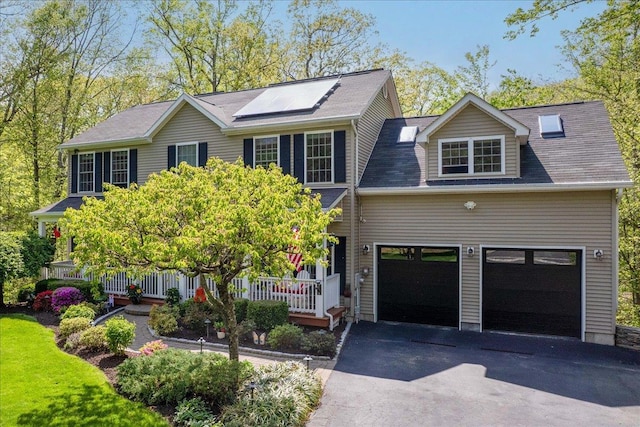 6 W Causeway, Cortlandt Manor, NY 10567 - view of front facade with a porch, an attached garage, roof mounted solar panels, and aphalt driveway