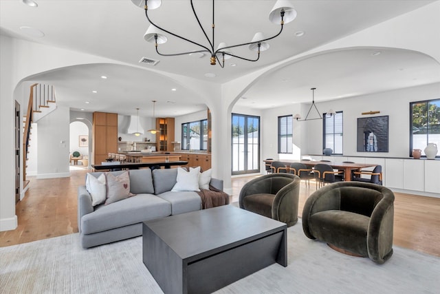 living room featuring a healthy amount of sunlight, a chandelier, and light wood-type flooring