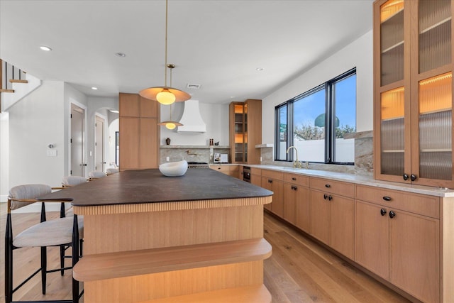 kitchen featuring a kitchen island, custom exhaust hood, hanging light fixtures, and light brown cabinets