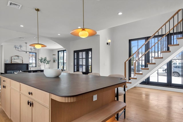 kitchen featuring pendant lighting, light brown cabinetry, light hardwood / wood-style floors, and a kitchen island