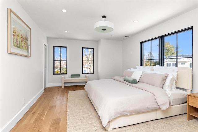 bedroom with multiple windows and light wood-type flooring