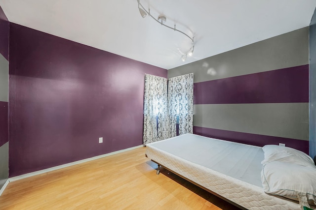 bedroom with hardwood / wood-style flooring and rail lighting