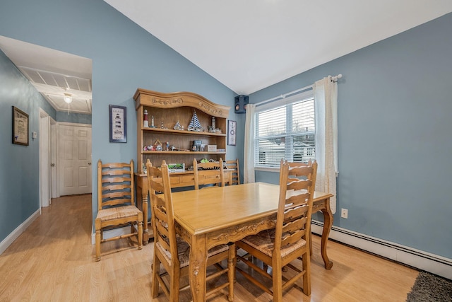 dining space featuring baseboard heating, lofted ceiling, and light wood-type flooring