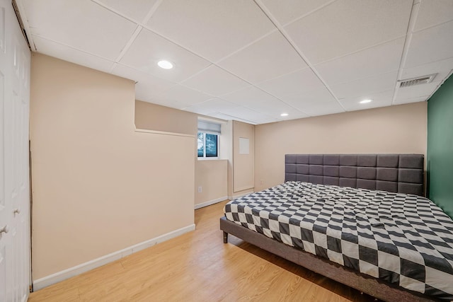 bedroom with a paneled ceiling and light wood-type flooring