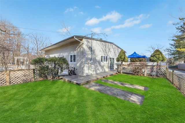 back of property featuring a wooden deck, a gazebo, and a lawn