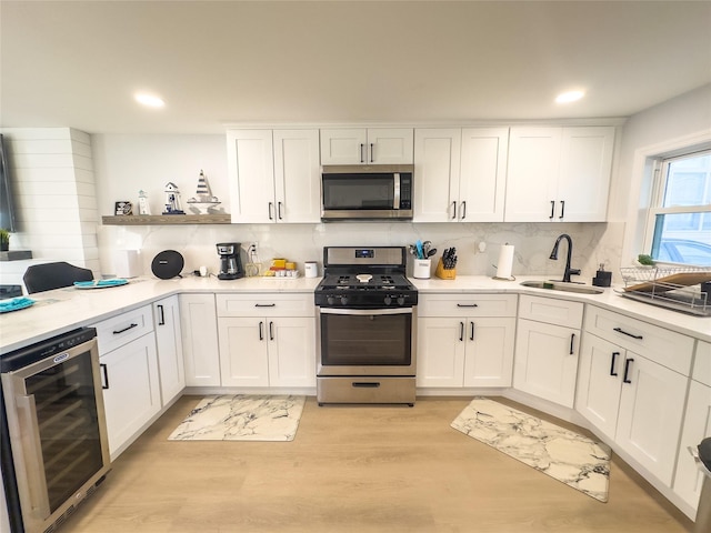 kitchen with sink, white cabinetry, stainless steel appliances, wine cooler, and decorative backsplash