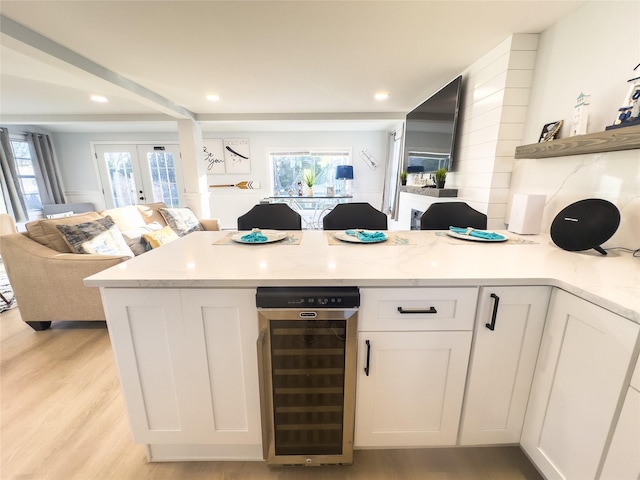 kitchen featuring white cabinetry, light stone countertops, a wealth of natural light, and beverage cooler