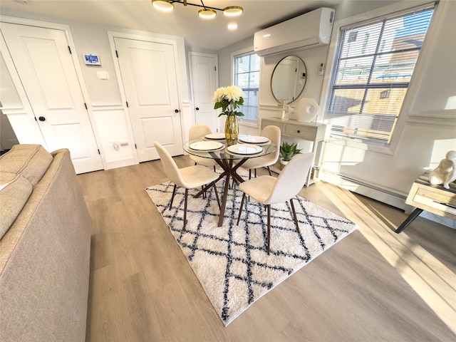 dining space with a baseboard radiator, a wall unit AC, and light hardwood / wood-style floors