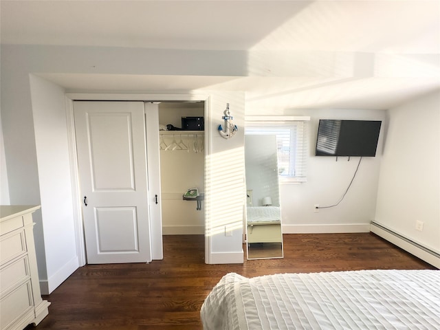 bedroom featuring a baseboard heating unit, dark wood-type flooring, and a closet