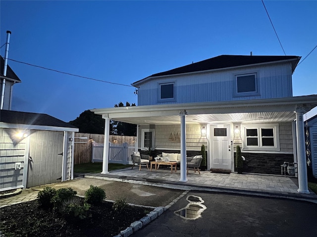 rear view of house with a storage unit, outdoor lounge area, and a patio area