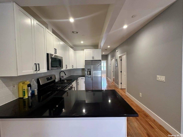 kitchen featuring sink, appliances with stainless steel finishes, light hardwood / wood-style floors, white cabinets, and kitchen peninsula