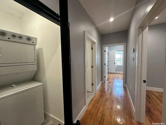 corridor featuring stacked washer and dryer and light wood-type flooring