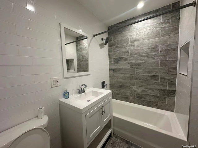 full bathroom with toilet, tiled shower / bath, tile walls, vanity, and backsplash