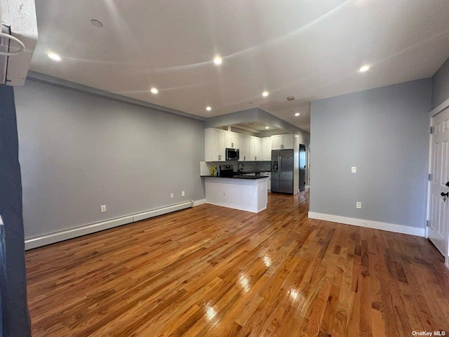 unfurnished living room featuring light wood-type flooring, sink, and baseboard heating