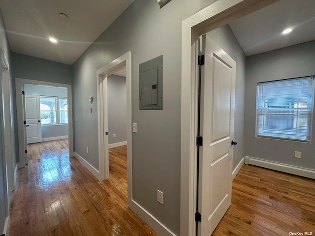 hall with a baseboard radiator, electric panel, and light wood-type flooring