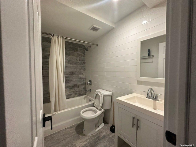 full bathroom with shower / tub combo with curtain, toilet, tile walls, vanity, and hardwood / wood-style flooring