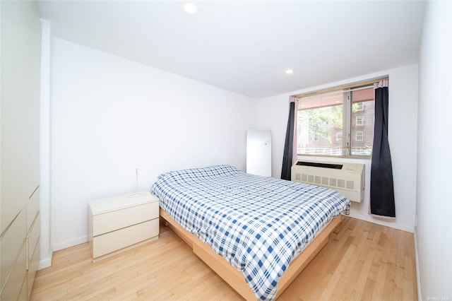 bedroom featuring light hardwood / wood-style flooring and an AC wall unit