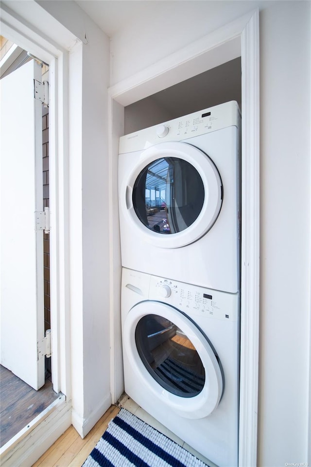 laundry area featuring stacked washer and dryer and wood-type flooring