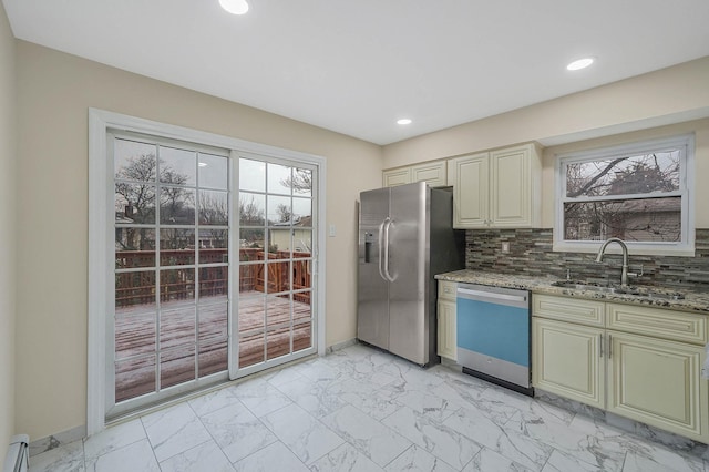 kitchen with cream cabinets, sink, decorative backsplash, stainless steel appliances, and light stone countertops