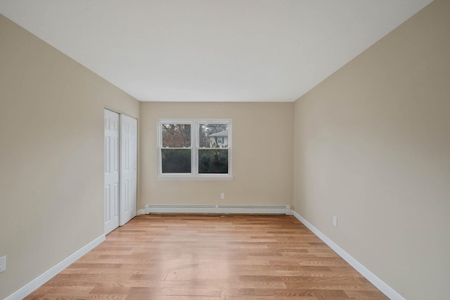 empty room featuring a baseboard heating unit and light wood-type flooring