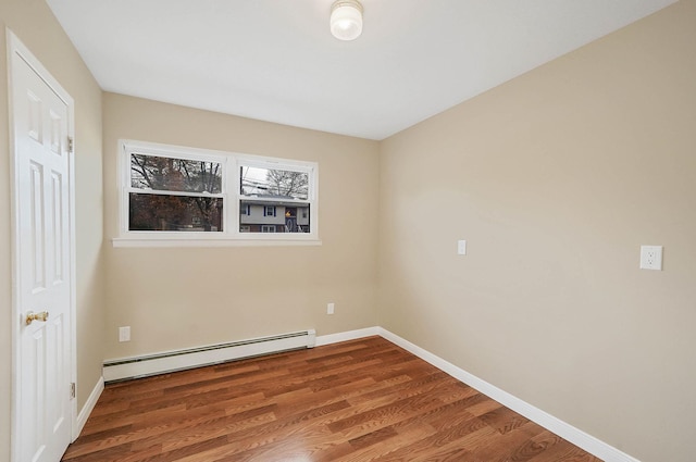 spare room with a baseboard heating unit and hardwood / wood-style flooring