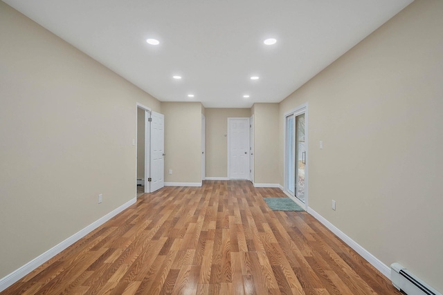 spare room with a baseboard radiator and light wood-type flooring