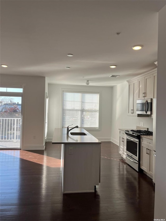 kitchen with stainless steel appliances, sink, an island with sink, and white cabinets