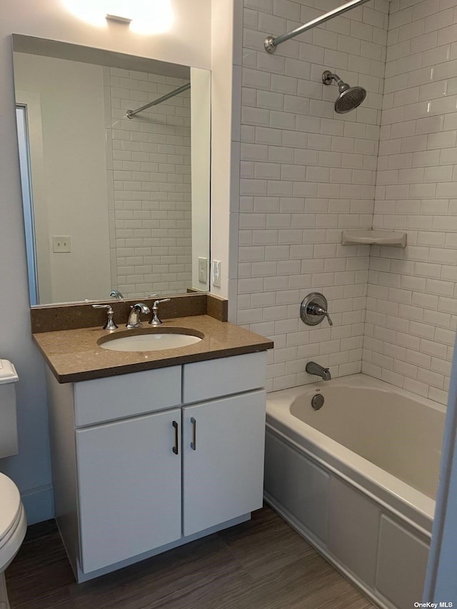 full bathroom featuring vanity, hardwood / wood-style floors, tiled shower / bath combo, and toilet