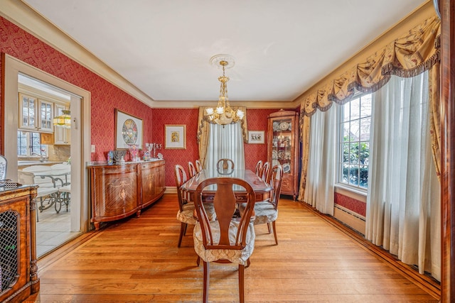 dining area featuring an inviting chandelier, a baseboard heating unit, and light hardwood / wood-style flooring