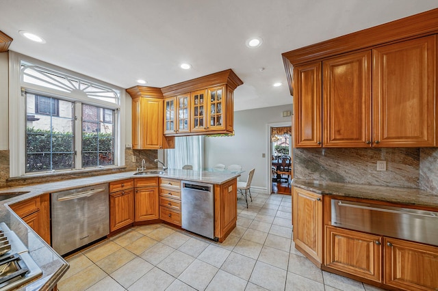 kitchen featuring light tile patterned floors, stainless steel dishwasher, kitchen peninsula, and stone counters