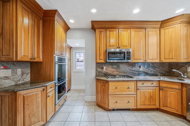 kitchen featuring sink, light tile patterned floors, backsplash, stainless steel appliances, and dark stone counters