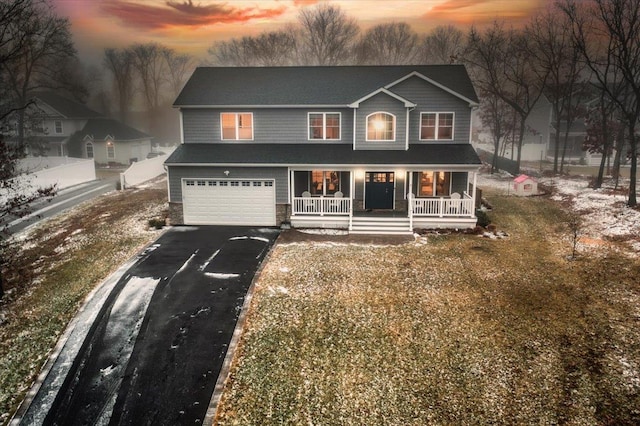 view of front of home with a porch, a garage, and a yard