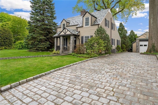 view of front of house featuring a garage, an outdoor structure, and a front lawn