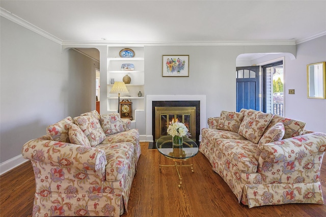 living room with dark hardwood / wood-style flooring, crown molding, and built in features