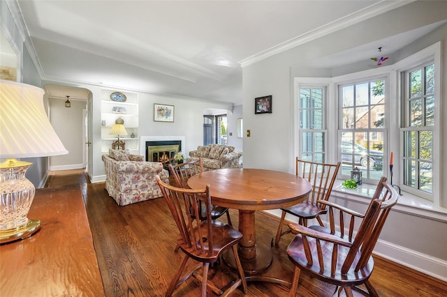 dining area with built in features, dark wood-type flooring, and ornamental molding