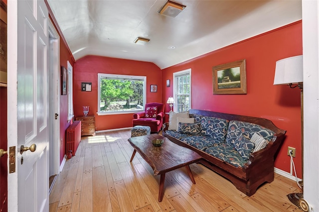 living room with lofted ceiling, radiator heating unit, and light wood-type flooring