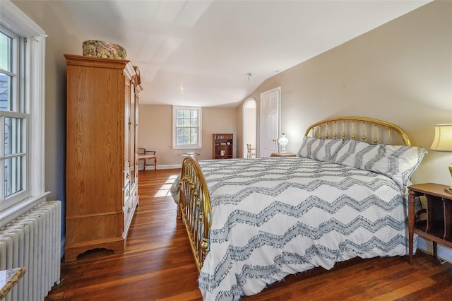 bedroom with radiator heating unit and dark hardwood / wood-style flooring