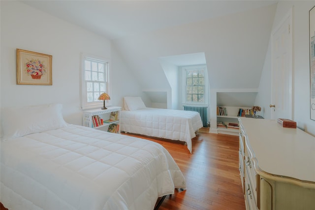 bedroom featuring lofted ceiling, radiator, and light hardwood / wood-style flooring