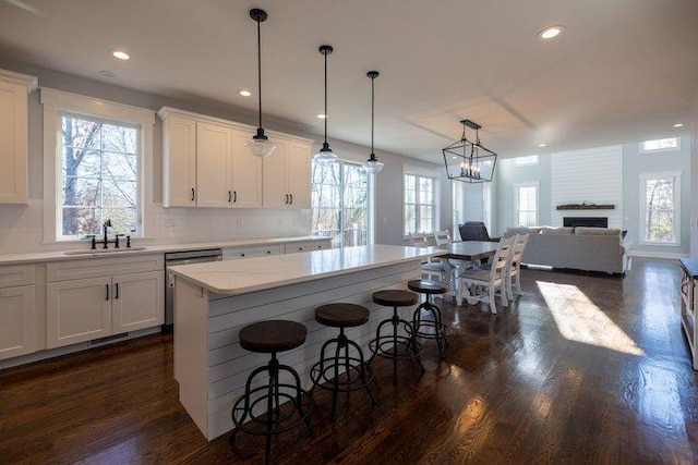 kitchen featuring white cabinetry, hanging light fixtures, sink, and a center island