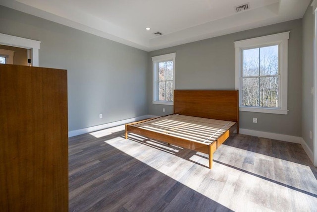 bedroom with dark wood-type flooring and a tray ceiling