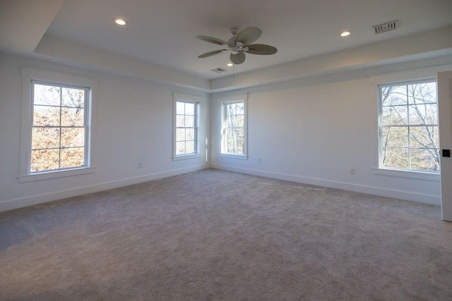 carpeted spare room with a tray ceiling and ceiling fan