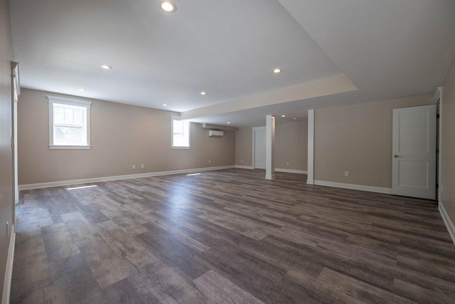 basement with a wall unit AC and dark hardwood / wood-style flooring