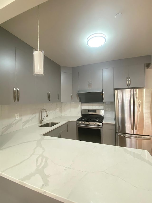 kitchen featuring pendant lighting, stainless steel appliances, sink, and gray cabinetry